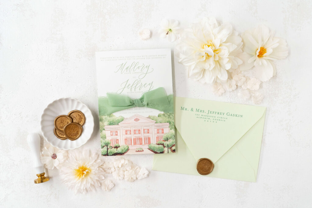 Custom wedding invitation wrapped in sage green silk ribbon, with a gold wax seal made custom. Watercolor illustration of the Tate House is also visible. The back of the envelope shows client's address and a deep euro-flap envelope in light green.