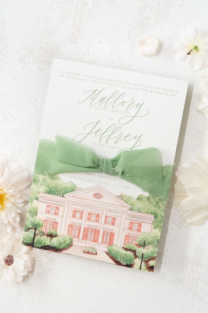 Formal wedding invitation for custom wedding invitation client tied with a sage green silk ribbon. Couple's names are written in sage green calligraphy atop a venue illustration in watercolor of the Tate House in North Georgia.