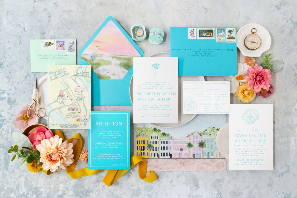 Flat lay of letterpress wedding invitations with custom watercolor map of Charleston, South Carolina and letterpress details, as well as beautiful vintage postage for wedding aesthetic.