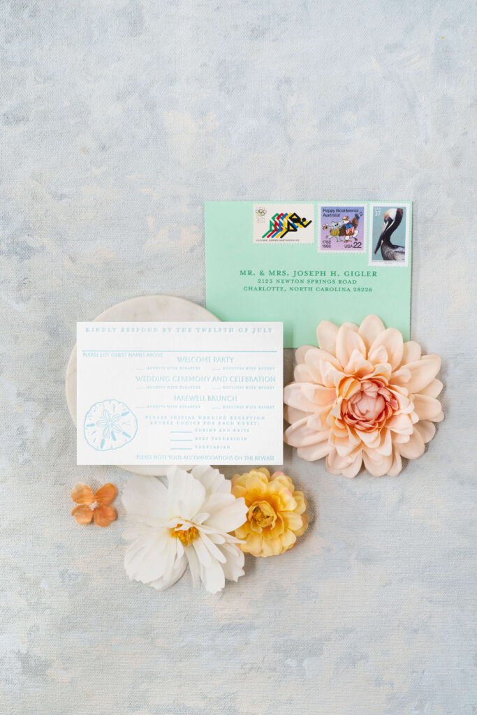 Letterpress RSVP card with sand dollar illustration and RSVP vintage stamps featuring track runners, USA and Australian stamp and a pelican stamp.