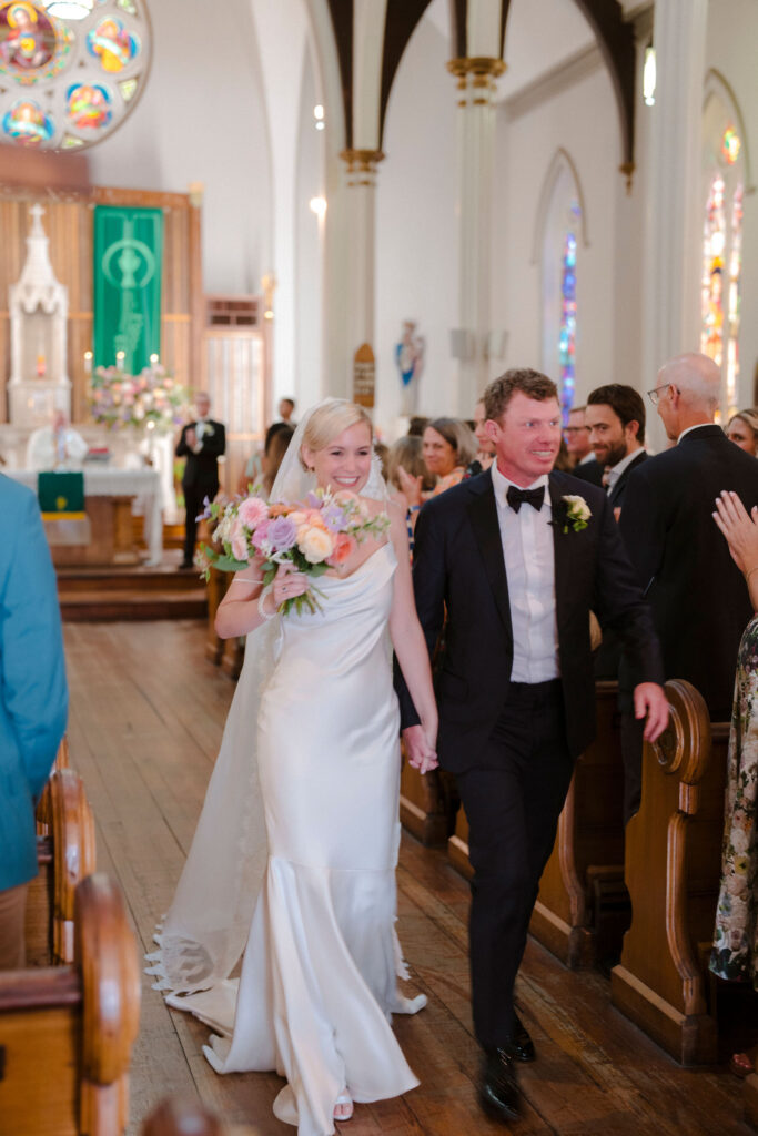 Bride and Groom hand-in-hand walking down the aisle after being married in St. Patrick's Catholic Church in Charleston, South Carolina.