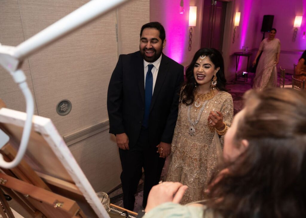 Wedding ceremony painter revealing painting to Indian bride and groom